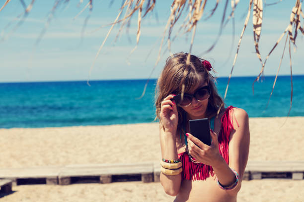 istock Girl holding a cellphone with sea/ocean background. 685549976