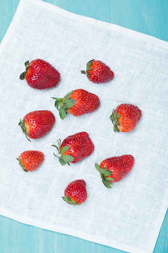 top view of whole fresh red strawberries on linen napkin on wooden tabletop, berries top view concept