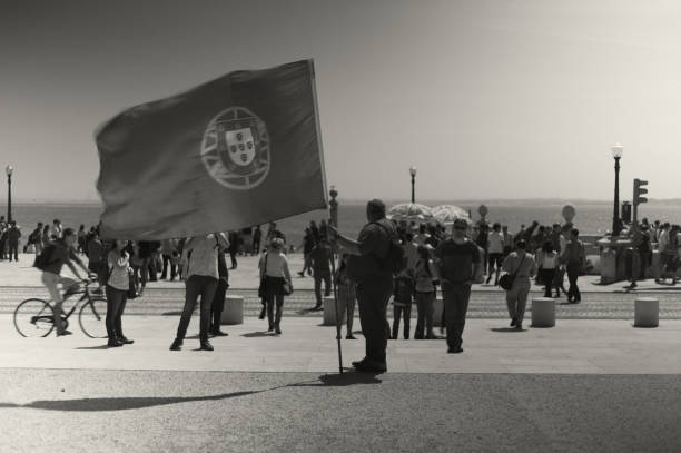 Lisbon, Portugal - April 13, 2017: A man holds a portuguese flag amidst the crowd in the Praça do Comércio square in Lisbon downtown.