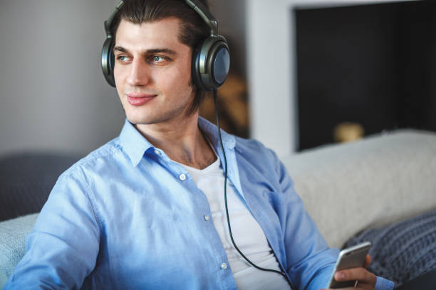istock Handsome guy sitting on sofa with headphones 685572328
