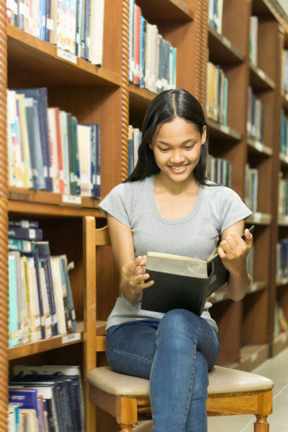 istock Portrait of a serious young student reading a book in a library 685578004