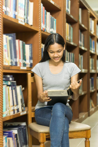 istock Portrait of a serious young student reading a book in a library 685582524