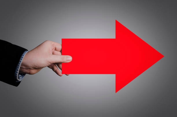 Businessman's hand holding a big red arrow pointing to the right