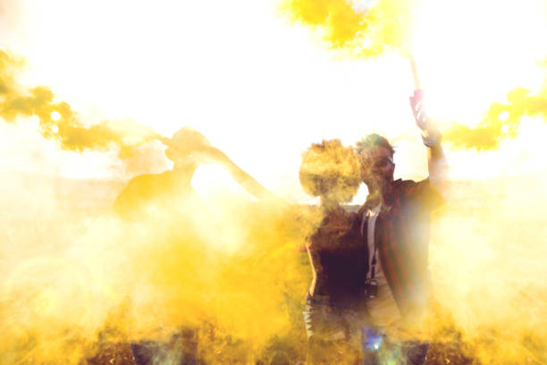 Friends holding smoke bombs having fun in a field during a road trip