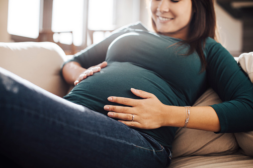 Future mother touching her stomach on sofa.