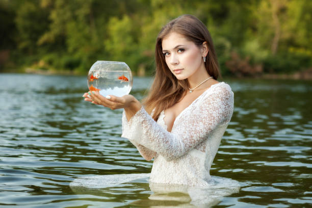 istock Woman stands in water, in her hands a goldfish. 685693948