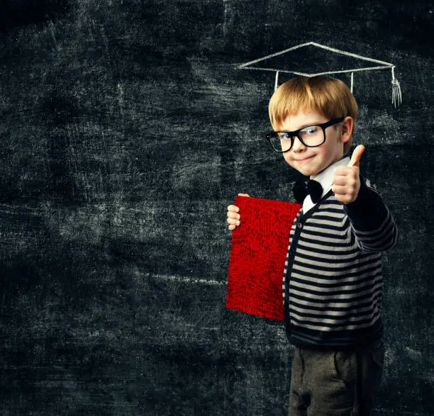 Photo of School Child Education Book, Kid in Glasses with Certificate, Graduation Hat on Blackboard Background, Thumbs Up