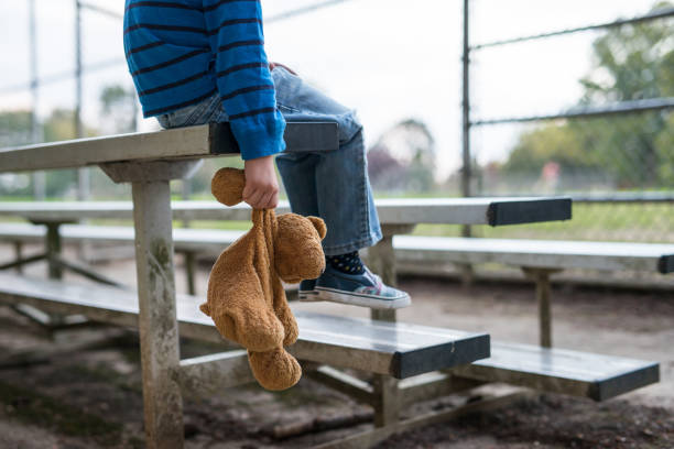 молодой мальчик сидит один на трибунах. - child playground small toy стоковые фото и изображения