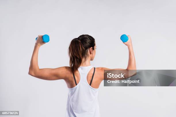 Attractive Young Fitness Woman Holding Dumbells Studio Shot Stock Photo - Download Image Now