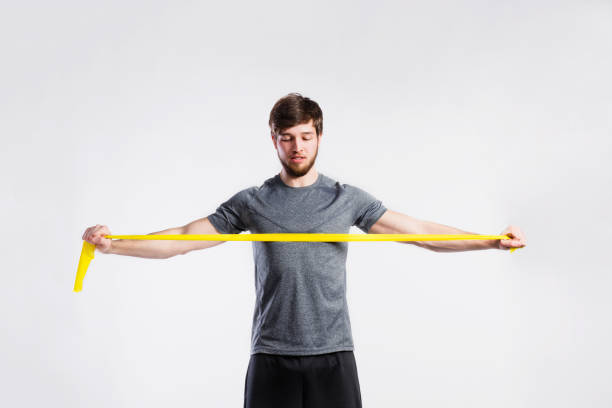 schöne fitness-mann arbeiten mit gummiband, studio-shot. - bizeps fotos stock-fotos und bilder