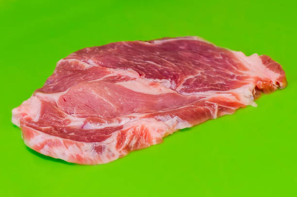 Raw pork steak on green background