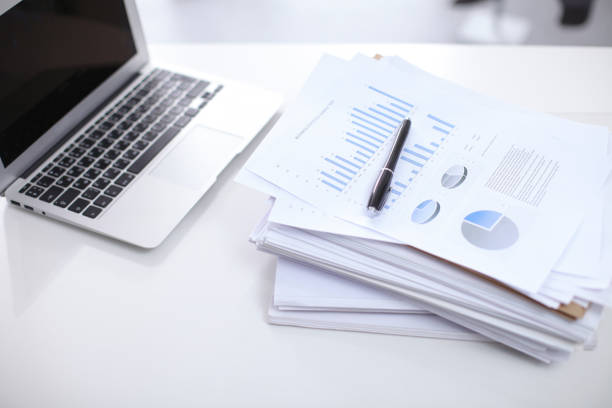 istock Office workplace with a laptop and financial documents on the light reflecting table 685761984