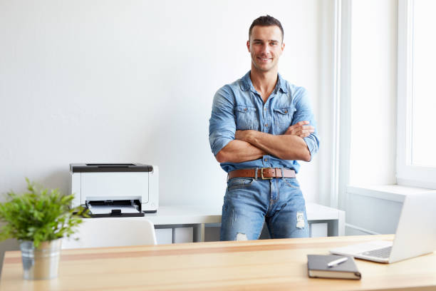 istock Happy man standing by his desk in office 685762118