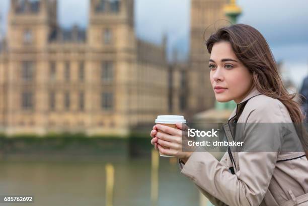 Beautiful Sad Depressed Or Thoughtful Young Woman In London On Westminster Bridge Over The River Thames Drinking Takeout Coffee By Big Ben Stock Photo - Download Image Now