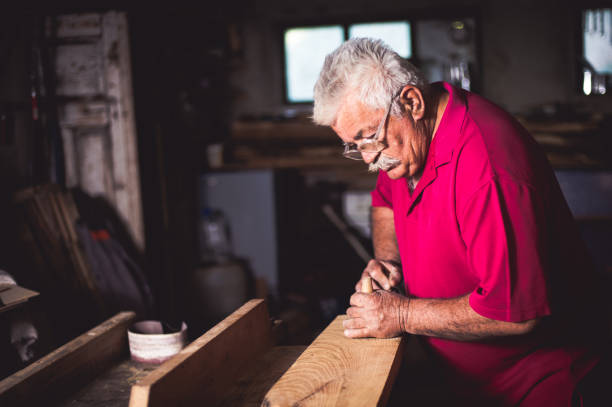 istock Carpenter scraping wood with antique planer 685765246