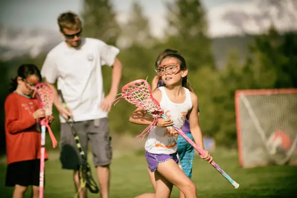 Father teaching girls team lacrosse