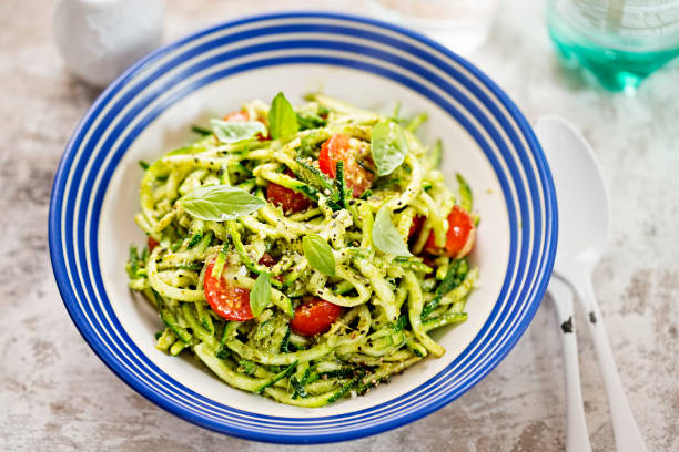 spirale zucchini spaghetti mit grünem pesto und kirschtomaten - zucchini stock-fotos und bilder