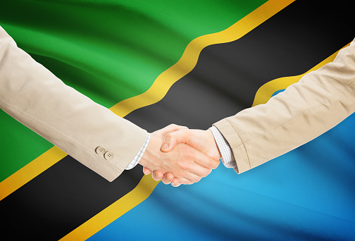 Businessmen shaking hands with flag on background - Tanzania