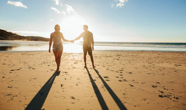 istock Couple walking on the beach together at sunset 685775216