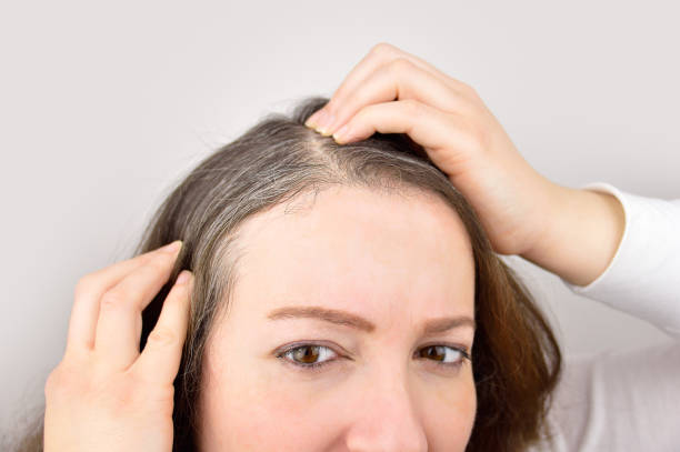 Young woman shows her gray hair woman is checking white hair while looking at the mirror white hair stock pictures, royalty-free photos & images