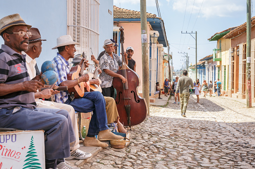 Trinidad, Cuba - March 22, 2017: Group of cuban men are playing traditional music on the streets of Trinidad whilst different people are dancing in the rythm of the music