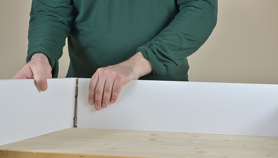 Man attaching two sides of a drawer set on working table