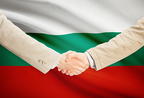Businessmen shaking hands with flag on background - Bulgaria