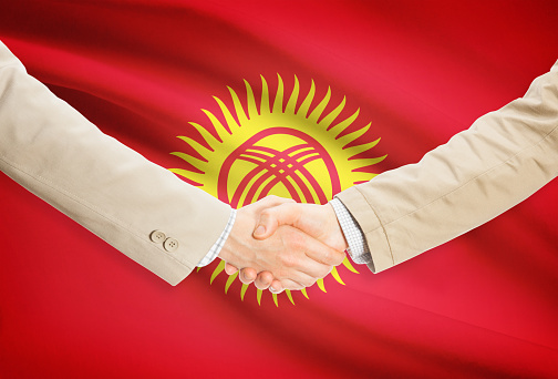 Businessmen shaking hands with flag on background - Kyrgyzstan