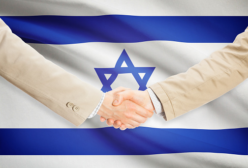 Businessmen shaking hands with flag on background - Israel