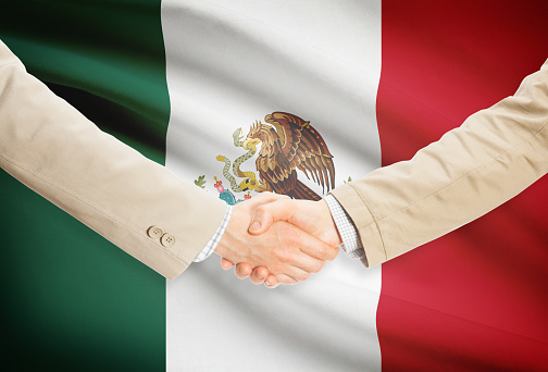Businessmen shaking hands with flag on background - Mexico