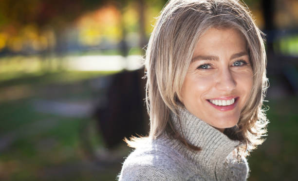 Portrait Of A Mature Woman Smiling At The Camera. Outside. Gray hairs. stock photo