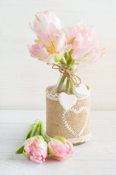 Pink tulips in rustic bottle Pink tulips in rustic bottle on a white wooden background. Pastel colors, greeting card concept white shabby chic desk stock pictures, royalty-free photos & images