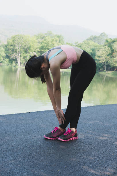 istock Female sport fitness runner getting ready for jogging outdoors on forest path in spring or summer. Healthy young asian woman stretching before running or after exercise in park. 685809836
