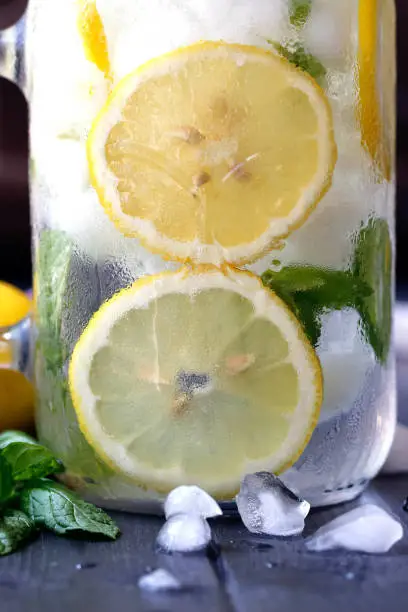 Healthy water with mint, sliced lemons and cucumbers. Diet drink. Sassy water.  Mason jar full with sliced fruits and vegetables. Mojito cocktail. Lemon slices with water and ice in the mason jar.