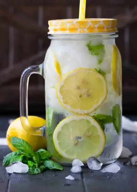 Healthy water with mint, sliced lemons and cucumbers. Diet drink. Sassy water.  Mason jar full with sliced fruits and vegetables. Mojito cocktail. Lemon slices with water and ice in the mason jar.