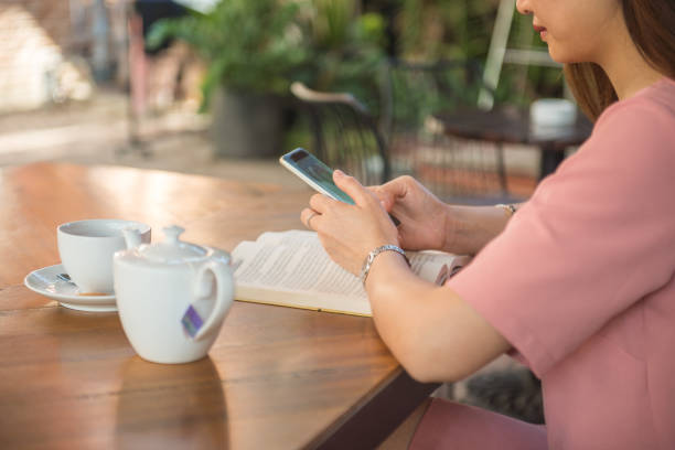 istock Side view of Asian girl texting when reading book 685819026