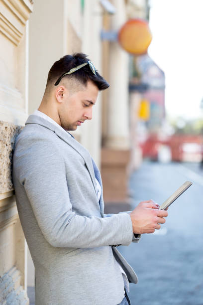 istock young businessman using tablet leaning to wall on street 685821914