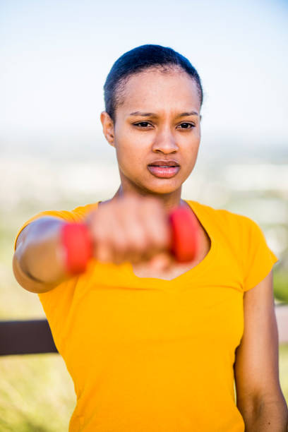 An attractive young African American training outdoors with weights and stretching