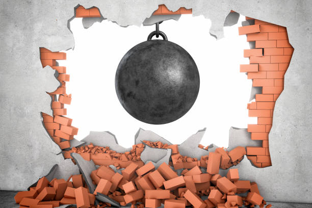 3d rendering of a large black wrecking ball hanging in a hole made in a brick wall with many bricks lying around stock photo