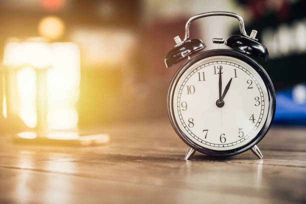 istock 1 o'clock time retro clock on wood table with sun light background 685835262