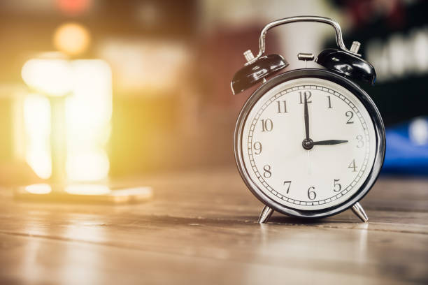 istock 3 o'clock time retro clock on wood table with sun light background 685836900