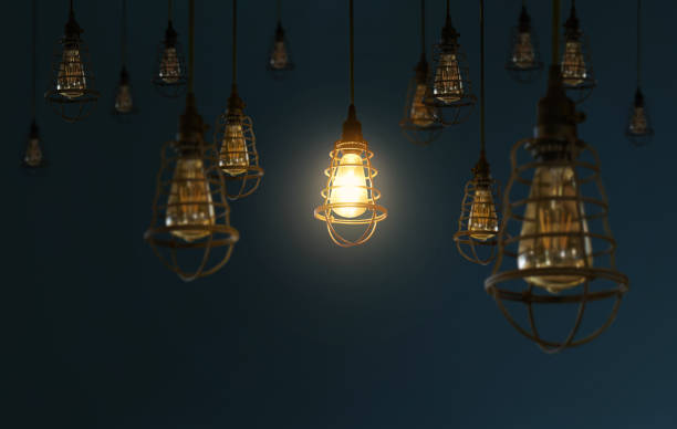 istock Hanging retro light bulbs decor on dark blue background with one isolated glowing . 685841496