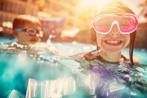 Kids swimming, laughing and having fun in hotel resort pool.\n\n