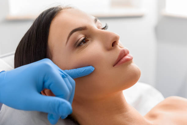 Therapeutic describing serene woman about beauty procedure Side view of unconcerned female with fair skin in surgical room. Doctor telling about injection pale complexion stock pictures, royalty-free photos & images