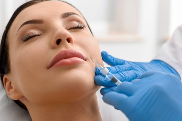 Calm woman during injection in face Close up serene girl lying in surgery room during botox procedure cheek stock pictures, royalty-free photos & images