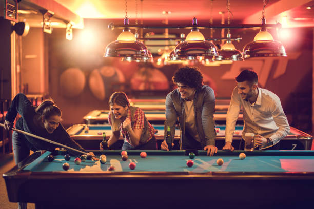 gruppo di amici felici che si divertono nel gioco del biliardo in una sala da biliardo. - pool game pool table aiming men foto e immagini stock