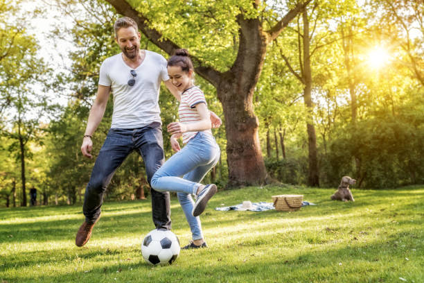 brodaty ojciec i nastoletnia córka grająca w piłkę nożną na letniej łące - activity sport teenager nature zdjęcia i obrazy z banku zdjęć