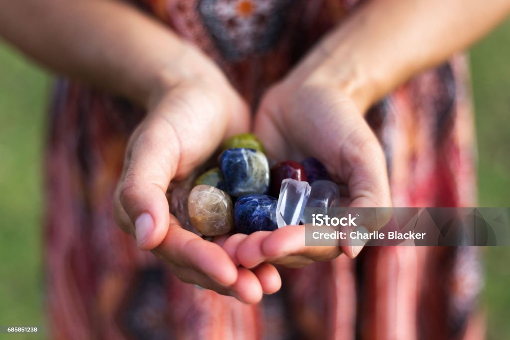 Handfull of Gemstones A young woman carefully holds a selection of vibrant gemstones as they reflect the soft sunlight. Crystal Stock Photo