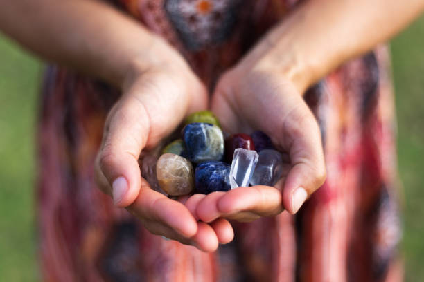 Handfull of Gemstones A young woman carefully holds a selection of vibrant gemstones as they reflect the soft sunlight. crystal stock pictures, royalty-free photos & images