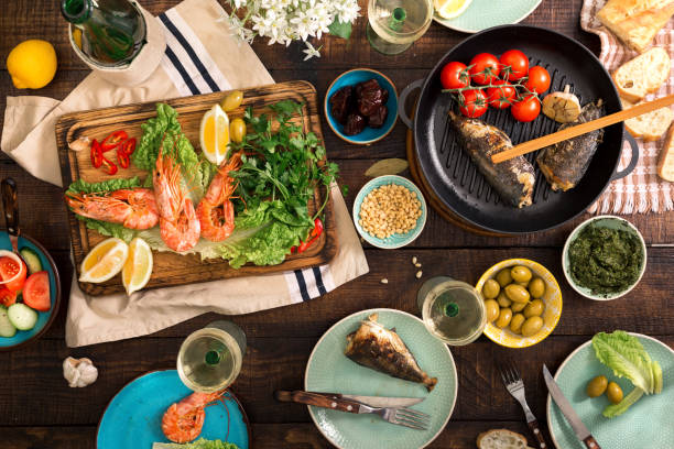 istock Dinner table with shrimp, fish grilled, salad, different snacks and white wine 685852958
